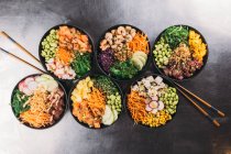 Ceramic bowls of various dishes of Asian cuisine on black metal surface — Stock Photo