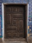Colpo esterno di legno invecchiato intagliato porta con sorprendente arredamento di piastrelle blu intorno, Uzbekistan — Foto stock