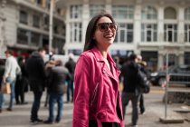 Stylish smiling woman in pink leather jacket on street — Stock Photo