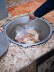 Crop person friggere grandi pezzi di carne sott'olio all'interno di calderone di metallo su piastrellato fuori cuoco — Foto stock
