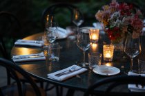 Mesa de ajuste decorada com velas e flores à noite no quintal — Fotografia de Stock