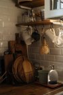 Intérieur de la cuisine avec des murs de carrelage blanc et beaucoup d'ustensiles et d'appareils composés sur des étagères et un comptoir — Photo de stock