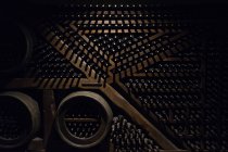 Delicato elegante volta del vino pieno di bottiglie sdraiato su scaffali in legno scuro con la luce splendente dall'alto — Foto stock