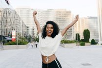 Excited African-American woman standing on street with hands up — Stock Photo