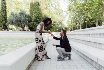Lächelnder Mann macht Frau im Park Heiratsantrag — Stockfoto