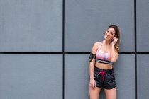 Confident sportswoman standing on street with earphones — Stock Photo
