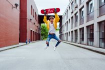 Feliz y emocionado adolescente saltando con monopatín - foto de stock