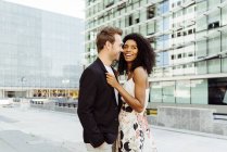 Smiling multiracial couple standing in modern city together — Stock Photo