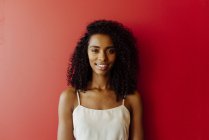 Retrato de mulher afro-americana sorridente em pé sobre fundo vermelho — Fotografia de Stock