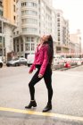 Trendy young woman in pink leather jacket laughing on street — Stock Photo