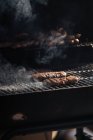 Raw burger patties roasting on grid of barbecue grill outdoors — Stock Photo