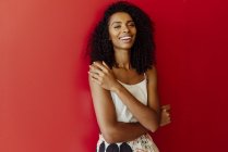 Портрет смеющейся афроамериканки, стоящей на красном фоне — стоковое фото