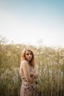 Junge blonde Frau posiert im hohen Gras am Seeufer — Stockfoto