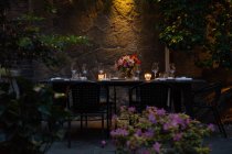 Сервировка стола со свечами и цветами ночью на заднем дворе — стоковое фото