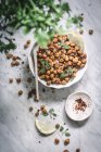Top view of bowl filled with baked spicy chickpeas served with herbs, lemon slices and spices — Stock Photo