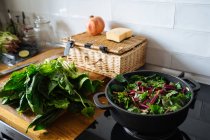 Spinach leaves in pot on gas stove and on wooden tabletop — Stock Photo