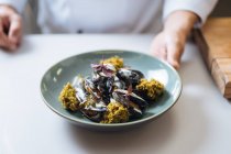 Close-up de chef que serve prato de frutos do mar nórdicos com mexilhões e molho de creme no prato — Fotografia de Stock