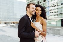 Sorrindo casal multirracial em pé na cidade moderna juntos — Fotografia de Stock