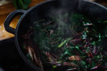 Cocinar hojas de espinaca en olla en estufa de gas - foto de stock