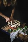 Cropped shot of woman creating lattice pie crust with straps of dough covering form with filling — Stock Photo