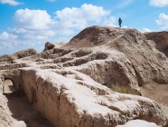 Vue latérale de l'homme courant sur les vestiges de l'ancien bâtiment en pierre dans un terrain sec sans fin de l'Ouzbékistan — Photo de stock