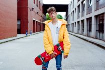 Teenager mit Skateboard steht auf Straße — Stockfoto