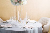 Tavola rotonda in stile elegante con porcellana bianca, bicchieri di cristallo e bouquet — Foto stock