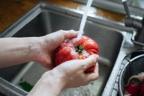 Frau wäscht frisches Gemüse in Küche — Stockfoto