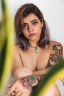 Naked young woman with body covered with tattoos looking at camera — Stock Photo