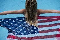 Visão traseira da mulher na piscina segurando bandeira americana — Fotografia de Stock