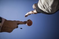 Hermanos jóvenes jugando baloncesto contra el cielo azul - foto de stock