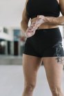 Athlète féminine avec les mains couvertes de craie debout dans le gymnase pendant l'entraînement — Photo de stock