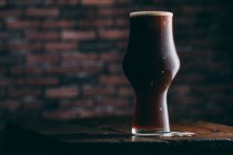 Stout beer in glass on dark background — Stock Photo