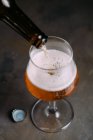 Разливать пиво из бутылки на сером фоне — стоковое фото