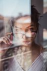 Sensual woman with eyeglasses looking at camera behind window — Stock Photo