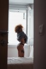 Чувственная женщина снимает свитер с окна в спальне — стоковое фото