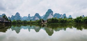 Small fishing village at Quy Son riverside and tranquil water with reflected mountains, Guangxi, China — Stock Photo