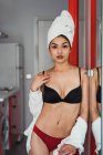 Sensuale giovane donna in lingerie e asciugamano sulla testa in piedi a casa e guardando la fotocamera — Foto stock