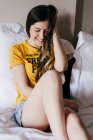 Hübsche lächelnde Frau, die auf dem Bett liegt und Haare berührt — Stockfoto