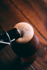 Pouring stout beer in glass from bottle on dark wooden background — Stock Photo