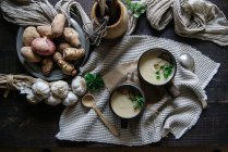 Tigelas de saborosa sopa de alcachofra Jerusalém com ingredientes em mesa de madeira rústica — Fotografia de Stock