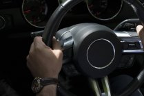 Крупным планом мужских рук на руле в автомобиле — стоковое фото