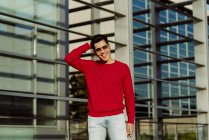 Giovane uomo sorridente in piedi di fronte a un edificio moderno — Foto stock