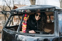 Ritratto di giovane donna in cappotto nero e occhiali da sole seduta all'interno dell'auto — Foto stock