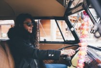 Молода жінка в чорному пальто і сонцезахисні окуляри за кермом ретро автомобіль — стокове фото