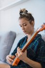 Junge Frau spielt Gitarre auf Sofa — Stockfoto