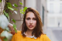 Pretty woman in yellow cardigan looking at camera on street — Stock Photo