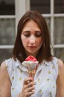Junge Frau in gemusterter Bluse mit Blick auf leckeres Eis auf unscharfem Hintergrund — Stockfoto