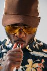 Black stylish man wearing sunglasses. He is vaping with an electronic cigarrete outdoor — Stock Photo