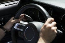 Gros plan des mains masculines sur le volant dans la voiture — Photo de stock